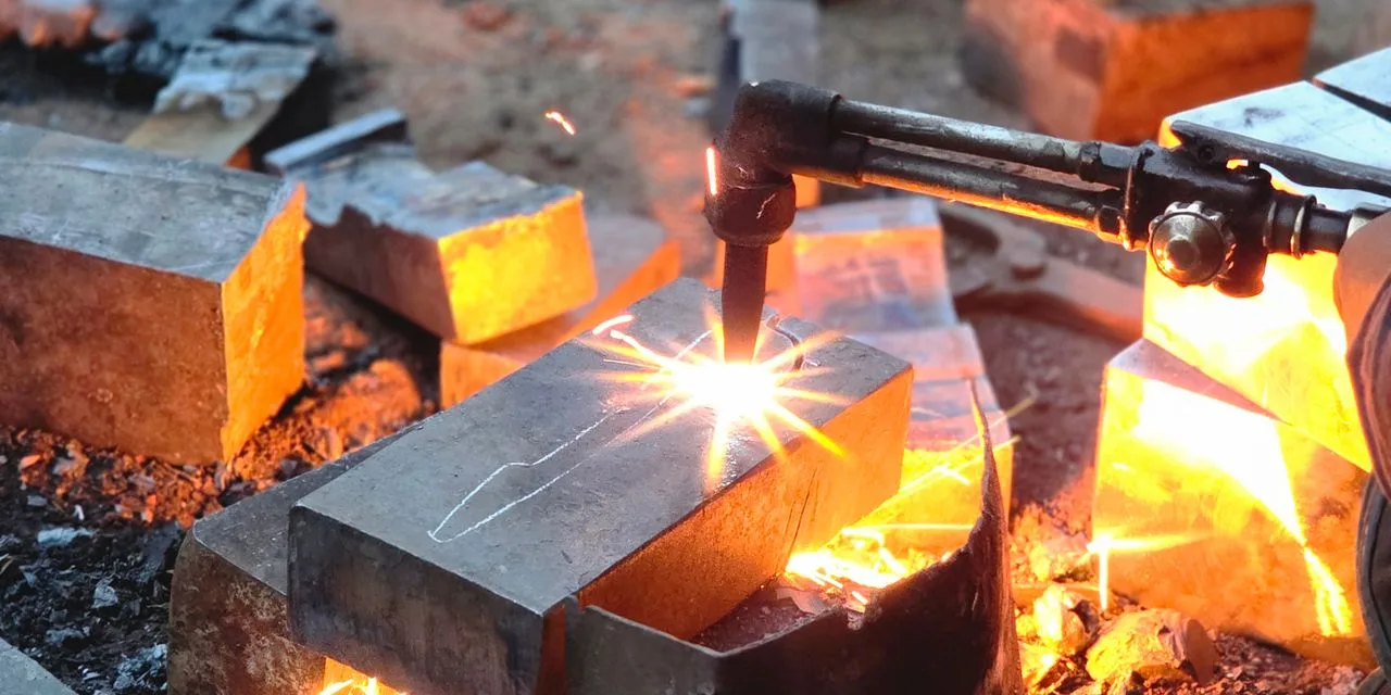 Stahlwerk CTM-250 ST: schweißen und trennen aus einem Gehäuse Ein Brennschnitt trennt einen Stahlblock, glühendes Metall fließt ab