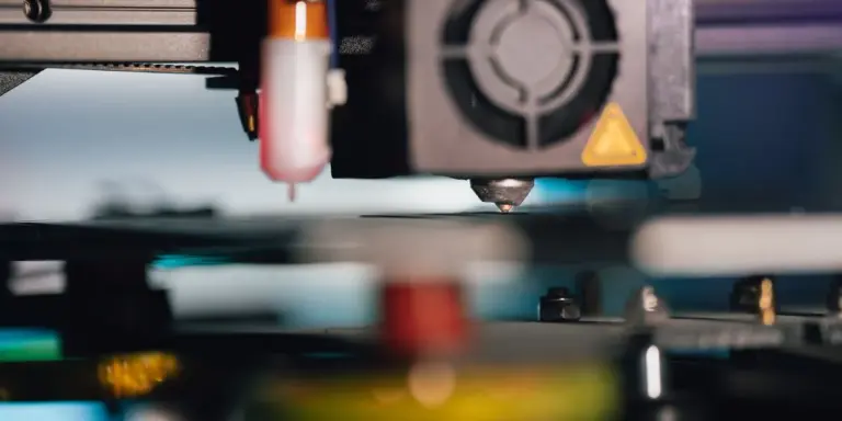 Ein Druckkopf mit Kühllüfter steht über dem Druckbett einer Maschine