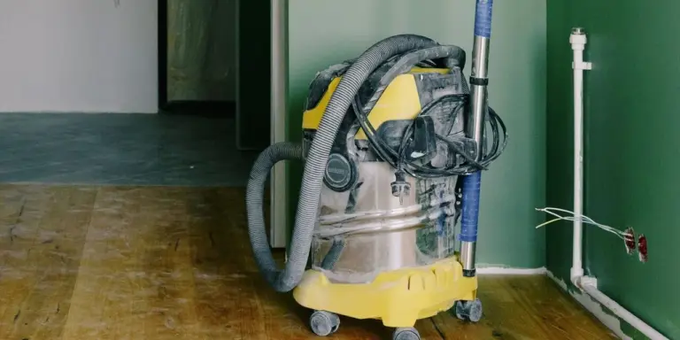 Ein Industriesauger mit Edelstahlbehälter auf Rollen, der Schlauch ist aufgerollt