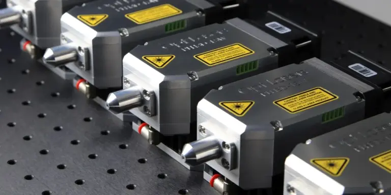 Mehrere Lasermodule mit Warnschildern stehen nebeneinander auf einer Lochplatte